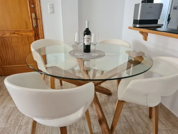 Runder Glastisch mit vier weißen Schalenstühlen