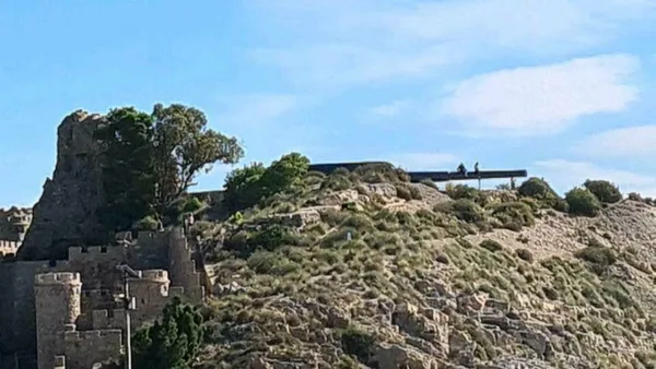 Verwitterter steinerner Wachturm auf einem Hügel über dem Meer