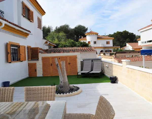 Terrasse mit Rattansofa neben einer Palme, dahinter das Haus